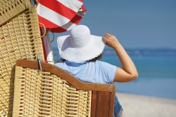 Frau mit Sommerhut im Strandkorb